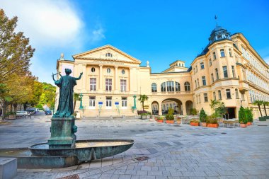 Viyana yakınlarındaki Baden 'de şehir meydanında küçük fıskiyeli tiyatro binası ve sanat heykeli manzarası. Avusturalya