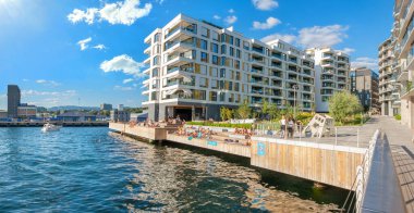 OSLO, NORway - 13 Ağustos 2015: Oslo limanında güneşli bir günde Aker Brygge kıyısı boyunca güneşlenen ve güneşlenen Norveçli insanlar