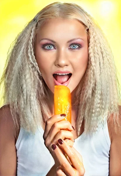 年轻快乐的金发女子在黄色明亮的背景上舔水果冰淇淋的时尚肖像 积极的夏季概念 — 图库照片