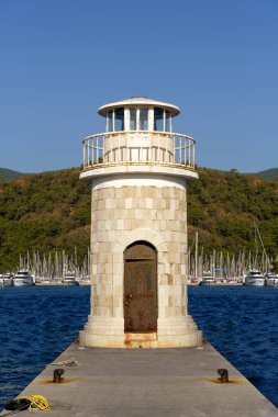 Limanın kıyısındaki deniz feneri kulesi. İskeledeki antik dekoratif deniz feneri. Deniz binaları konsepti. Yüksek kalite fotoğraf