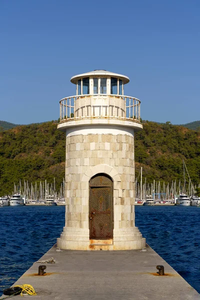 Limanın kıyısındaki deniz feneri kulesi. İskeledeki antik dekoratif deniz feneri. Deniz binaları konsepti. Yüksek kalite fotoğraf