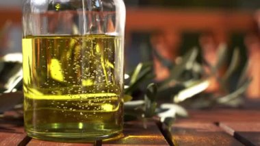 Güneşli bir günde, bir şişeye zeytinyağı dökülür. Ağaç dallarıyla süslenir. Olgun taze zeytinlerle. Akdeniz mutfağı için yağ besin maddesi. Tarım ve hasat kavramı