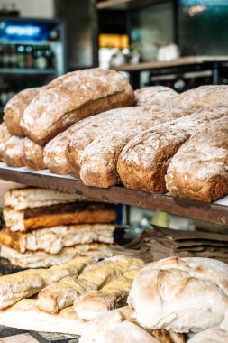 Tezgahın raflarında somunlar dolusu ekmek. Taze, ev yapımı buğday, tam tahıllı ekmek ve hamur işi. Yüksek kalite fotoğraf
