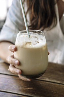 Elindeki buzlu latte. Bir bardak soğuk kahve. Sokağın karşısındaki bir kafede elinde süt olan bir kız. İçki, yaşam tarzı, şehir konsepti. Yüksek kalite fotoğraf