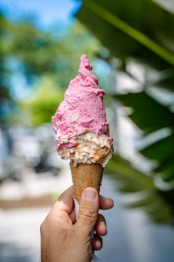 Elde dondurma. Sıcak bir yaz gününde sokağın arka planında dondurmalı gözleme külahı. Sokak yemekleri, tatlılar, tatlı konsepti. Yüksek kalite fotoğraf