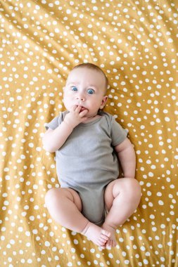 Cheerful baby lies on the bed in the childrens room. Caucasian baby smiles. High quality photo