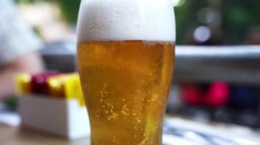 Sokağın arka planında bardakta bira. Bira barında altın ve köpüren alkollü içeceklerle dolu bir masa. Yüksek kaliteli FullHD görüntüler