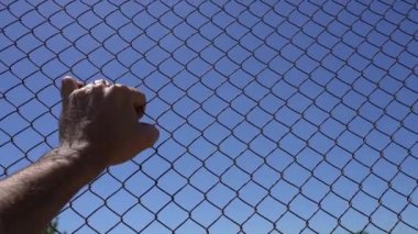 Hand on an iron fence against the sky. Conclusion, border, emigration, despair, help concept. High quality FullHD footage