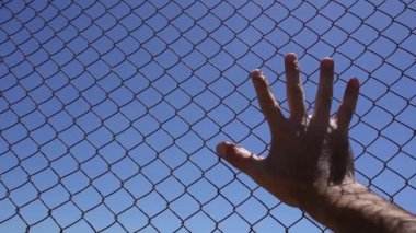 Hand on an iron fence against the sky. Conclusion, border, emigration, despair, help concept. High quality FullHD footage