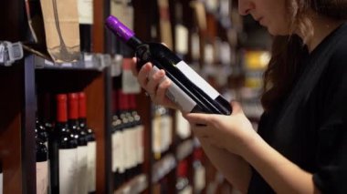 Buenos Aires, Arjantin - 29 Ocak 2023: Dükkânda şarap seçimi. Bir kız içki dükkanından bir şişe şarap seçiyor. Yüksek kaliteli FullHD görüntüler