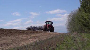 Çiftçilerin tarlalarındaki traktör tarlayı sürüyor ve toprağı işliyor. Tarım, tarım işi hasat konsepti. Yüksek kaliteli FullHD görüntüler