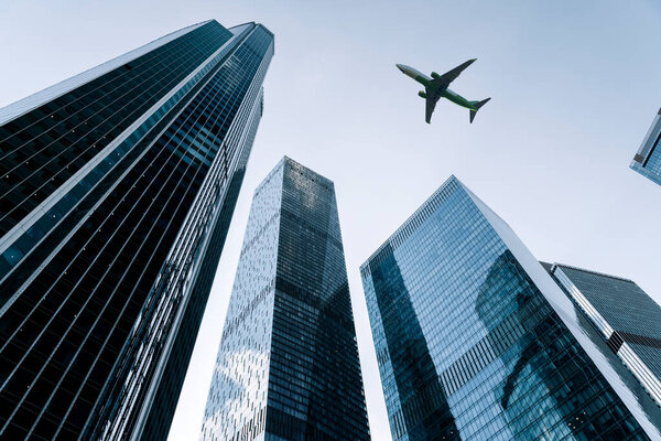 Airplane flying on business skyscrapers of financial center. Travel, economy, cargo, transportation concept. High quality photo