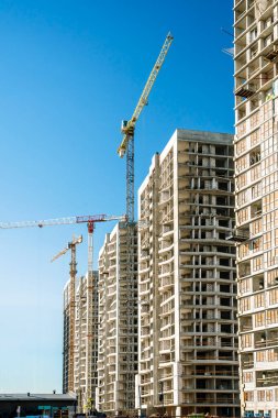 İnşaat alanı. Yeni apartman gökdeleni olan bir vinç. İnşaat endüstrisi teknolojisi, iş dünyası, şehir konsepti. Yüksek kalite fotoğraf