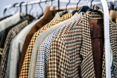 Second hand vintage clothes in a store on sale. Fashionable European used retro jeans, t-shirts, dresses, pants and accessories. Recycling and life extension for clothes concept. High quality photo