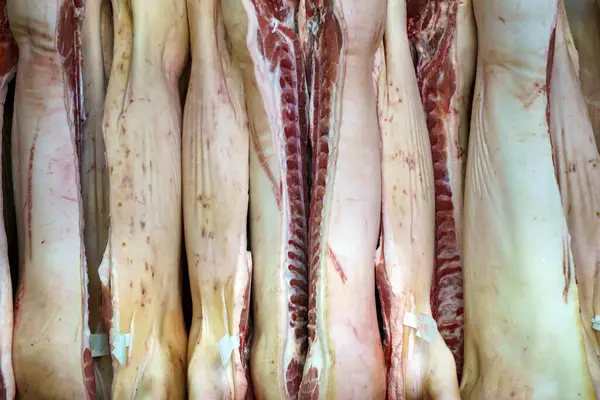 Pork meat in production. Fresh pork carcasses in a meat factory warehouse. High quality photo