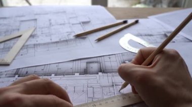 Masaya mimari mühendisliği tasarımı çizimi. Mimarlar stüdyodaki masada çalışırlar. İnşaat tasarımı ve planı. Yüksek kaliteli FullHD görüntüler