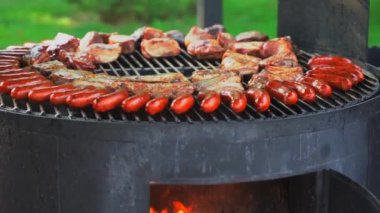 Et ve ateşte sosisli barbekü ızgarası. Et ızgarada kızarıyor. Yüksek kaliteli FullHD görüntüler