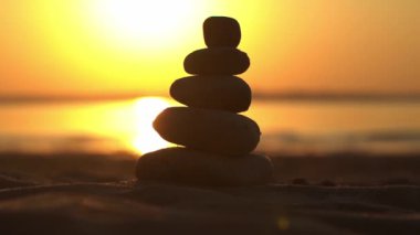 Zen taşları arka plan. Sahilde günbatımının arka planında taş piramidi. Rahatla, denge, sakinlik, konsept. Yüksek kaliteli FullHD görüntüler