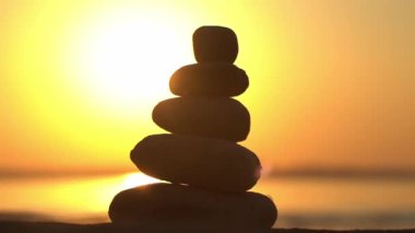 Zen taşları arka plan. Sahilde günbatımının arka planında taş piramidi. Rahatla, denge, sakinlik, konsept. Yüksek kaliteli FullHD görüntüler