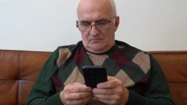 Sunbae evde akıllı telefon kullanıyor. Yaşlı adam internet kullanıyor. Yüksek kaliteli FullHD görüntüler