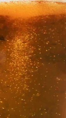 Bira baloncukları altın kaplama. Bardakta bira. Dikey video. Yüksek kaliteli FullHD görüntüler