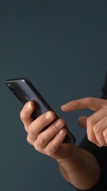 Akıllı telefon kullanan bir adam. Koyu arkaplanda akıllı telefon kullanıcısı. Dikey video. Yüksek kalite 4k görüntü