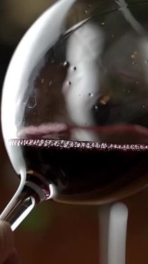 Kırmızı şarap kadehi. Kırmızı şarap bardakta parlıyor. Dikey video. 