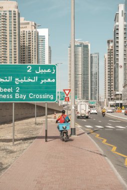 Dubai, BAE - 30 Nisan 2026: Dubai sokaklarında Asyalı göçmen işçi. Dubai, Birleşik Arap Emirlikleri 'nde bir cadde boyunca yürüyen Asyalı bir göçmenin yüksek kaliteli fotoğrafı. Giyinik.