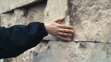 Şehrin tarihi yerinde bir kadın eli antik bir taş duvara dokunuyor. Seyahat, eğlence, tarih konsepti. Yüksek kaliteli FullHD görüntüler