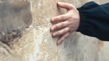 Şehrin tarihi yerinde bir kadın eli antik bir taş duvara dokunuyor. Seyahat, eğlence, tarih konsepti. Yüksek kaliteli FullHD görüntüler