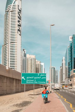 Dubai, BAE - 30 Nisan 2025: Dubai sokaklarındaki Asyalı göçmen işçi. Dubai, Birleşik Arap Emirlikleri 'nde bir cadde boyunca yürüyen Asyalı bir göçmenin yüksek kaliteli fotoğrafı. Giyinik.