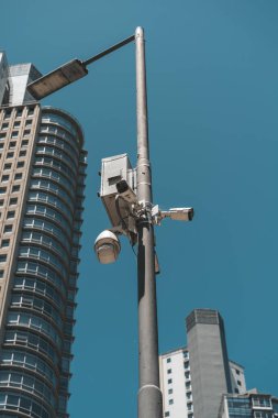 Şehir ortamında bir direğe monte edilmiş sokak güvenlik kamerasının yakın çekimi. Kamu güvenliği kavramı, modern şehir altyapısı, video izleme ve elektronik gözetim. İdeal