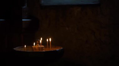 Bir Hıristiyan tapınağında mum yakmak karanlıkta dua etmek için bir ikonun önünde. Din, inanç, dua kavramı. Yüksek kaliteli FullHD görüntüler