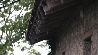 Yağmur. Eski bir evin kiremitli çatısından akan yağmur damlaları. Yüksek kaliteli FullHD görüntüler