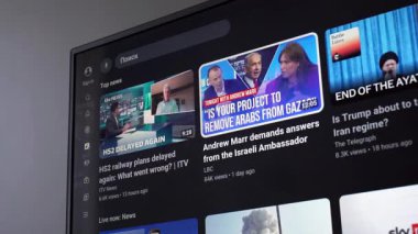 YouTube 'da küresel haber videolarını gösteren bir televizyon ekranının görüntüsü. Sahne modern bilgi tüketimini, dijital haber akışını, medya aşırı yükünü ve psikolojik