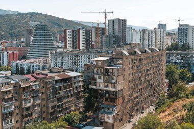 Gürcistan 'ın Tiflis kentinin panoramik manzarası, yukarıdan ele geçirildi. Görüntü, eski Sovyet döneminden kalma panel konutlarla şehir evriminin altını çizen yeni yerleşim yerlerindeki yüksek binalar arasında çelişiyor.