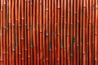 A vibrant red bamboo wall creating a striking and exotic natural background. The colorful bamboo stalks deliver a bold and stylish look, perfect for use in Asian-inspired design, spa interiors, eco