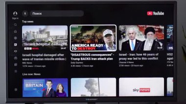 YouTube 'da küresel haber videolarını gösteren bir televizyon ekranının görüntüsü. Sahne modern bilgi tüketimini, dijital haber akışını, medya aşırı yükünü ve psikolojik