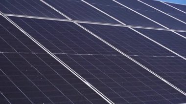 Yaz boyunca güneşli bir kırsal alana monte edilmiş güneş panellerinin havadan veya yerden çekilmiş görüntüleri. Video, yenilenebilir enerjinin gücünü ve güneş teknolojisinin