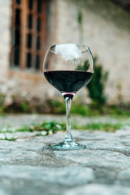 Tek bir kadeh kırmızı şarap, eski bir şarap mahzeninin önünde zarif bir şekilde duruyor. Geleneksel Avrupa şarap imalatının sonsuz cazibesini yakalıyor. Fransa veya İtalya 'da geçen resimde kırsal kesime vurgu yapılıyor