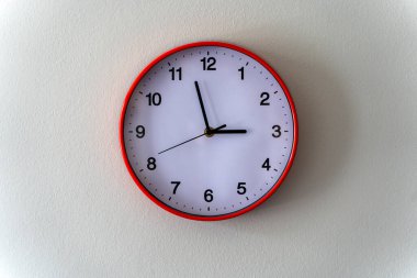 Sade açık renkli bir duvara asılı yuvarlak duvar saatinin minimalist fotoğrafı. Temiz kompozisyon zamanın, rutinin, yapının ve basitliğin geçişini vurgular. Zamanı resmetmek için ideal