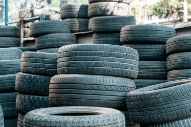 Kullanılmış ve yıpranmış araba lastikleri, aşınma izleri, çatlaklar ve birikmiş toz yığını. Görüntü otomotiv atıkları, geri dönüşüm sorunları, çevre kirliliği ve kauçuğun etkisini yansıtıyor