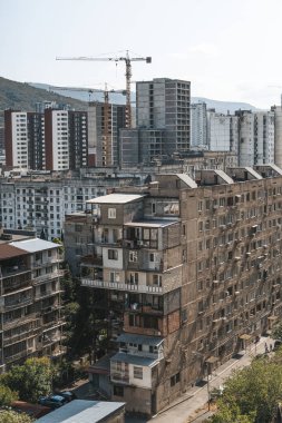 Gürcistan 'ın Tiflis kentinin panoramik manzarası, yukarıdan ele geçirildi. Görüntü, eski Sovyet döneminden kalma panel konutlarla şehir evriminin altını çizen yeni yerleşim yerlerindeki yüksek binalar arasında çelişiyor.