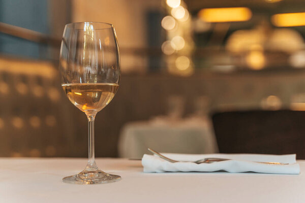 Glass of White Wine on Restaurant Table. Elegant Dining Atmosphere. High quality photo