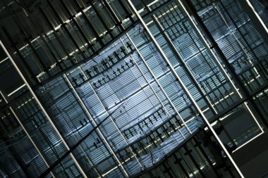 Fütürist Geometrik Mimari soyut arka plan. Mavi ışıklandırmalı modern cam ve metal yapının soyut geometrik deseni, teknolojiyi, yeniliği ve çağdaşlığı simgeliyor.