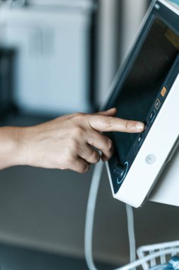 Hastane ortamında ekranda hayati belirtileri olan modern bir tıbbi hasta monitöründe bir tuşa basıyorum..