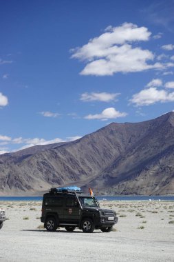Ladakh, India - August 24th, 2022: SUV car at Pangong Lake, world's highest saltwater lake, offroading in mountains of Ladakh.