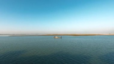 Geniş bir nehrin ortasında, temiz ve güzel gökyüzünün altında iki adam..