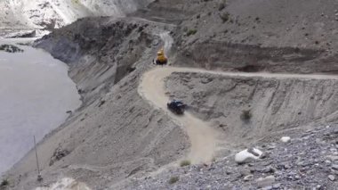 JCB 'nin dağ yolunda çekilmiş görüntüleri ve o yolda siyah bir SUV araba sürüşü..