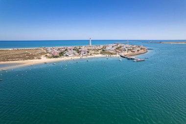 Portekiz 'in Algarve Turizm Bölgesi' ndeki Ria Formosa doğal parkını koruyan bariyer adalarından biri olan Praia do Farol sahilindeki Santa Maria deniz feneri adasının hava manzarası.